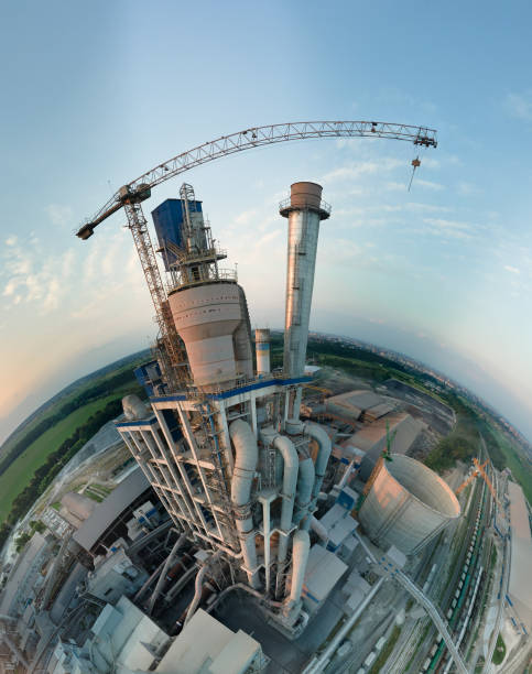 Aerial view from high altitude of little planet earth with cement factory high concrete structure and tower crane at industrial production area in evening. Manufacture and global industry concept stock photo