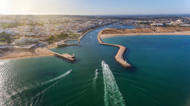 Aerial view from sky of Portuguese coastline of Algarve zone of Lagos city. Boats and ships are moving in the direction of the port. Sunny day. stock photo