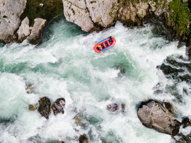 Aerial view of a group of men and women white water river rafting Drone point of view of men and women white water river rafting inflatable raft stock pictures, royalty-free photos & images