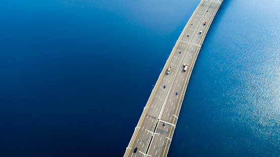 Aerial view of a high way road on the bridge over blue water