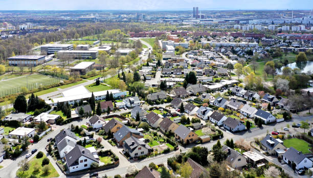 Aerial view of a housing estate on the outskirts of the city of Wolfsburg in Germany with a school in the background and factories on the horizon. stock photo