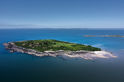Aerial view of a small island in a bay of seawater off the coast of Scotland on a summer morning
