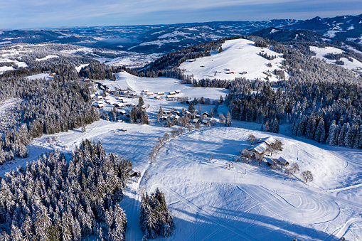 Aerial view of a winter landscape in a ski resort with mountains and forest. Photographed at the Boedele, Vorarlberg