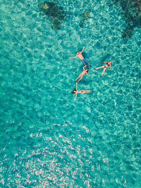 Aerial view of a young family floating and swimming on beautiful beach at Greek island stock photo