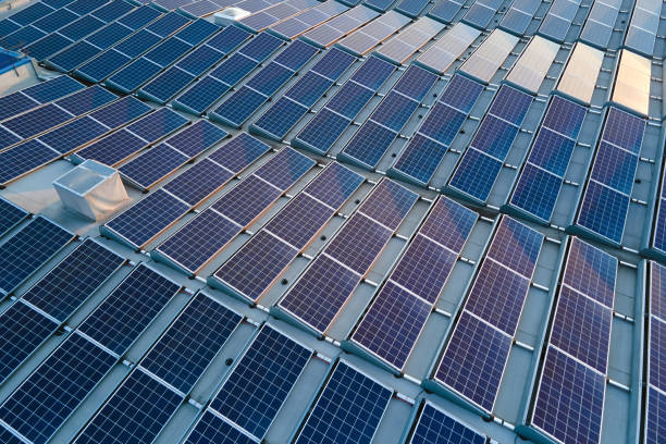 Aerial view of blue photovoltaic solar panels mounted on industrial building roof for producing green ecological electricity. Production of sustainable energy concept stock photo
