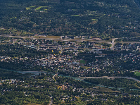 Aerial view of Canmore downtown located in Bow Valley in Alberta, Canada in the Rocky Mountains viewed from Ha Ling Peak with Bow River, buildings and Trans-Canada Highway in autumn season.