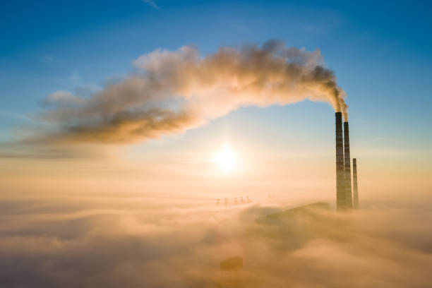Aerial view of coal power plant high pipes with black smoke moving up polluting atmosphere at sunrise. stock photo