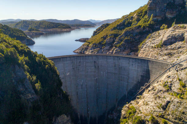 Aerial view of enormous cement dam on a sunny day in tasmania, Australia Aerial view of enormous cement dam on a sunny day in Tasmania, Australia dam stock pictures, royalty-free photos & images