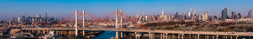Aerial view of Kosciuszko Bridge surrounding with the industrial district of Williamsburg, with the remote view of Manhattan in the backdrop.