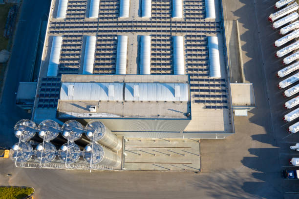 Aerial View of Modern Distribution Warehouse with Stainless Steel Storage Tanks Aerial view of modern industrial warehouse, storage building and stainless steel storage tanks. Solar panel photovoltaic installation on a roof of factory, alternative electricity source, sustainable resources concept. batteries stock pictures, royalty-free photos & images