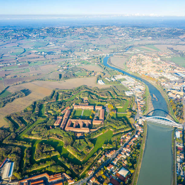 Aerial view of modern six-star hexagon shaped fort Cittadella of Alessandria on winding river Tanaro. Piedmont, Italy. Alps in the background. Bridge Ponte Meier connects fortress to town centre stock photo