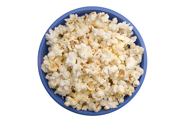 Aerial view of popped popcorn in a blue bowl on white table stock photo