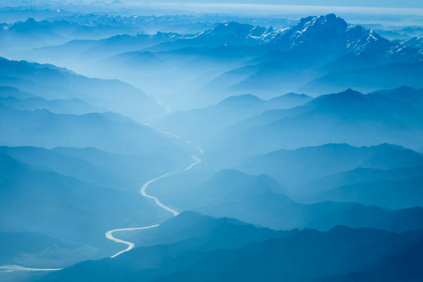 Aerial View of River Winding Through Foggy Himalyan Mountains stock photo