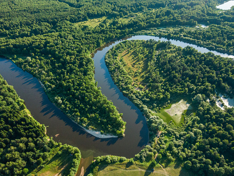 Aerial view of the beautiful landscape, the winding river among the forest at sunset