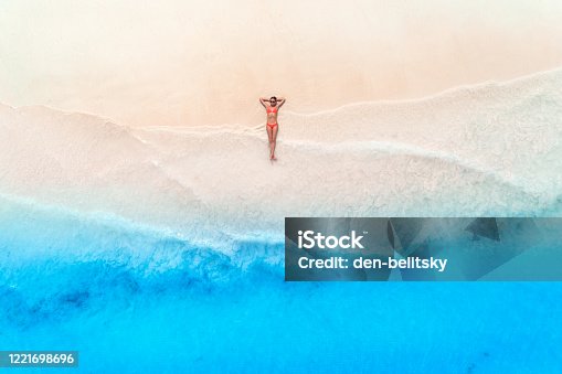 istock Aerial view of the beautiful young woman lying on the white sandy beach near sea with waves at sunset. Summer travel. Top view of slim girl, transparent blue water. Indian Ocean in Zanzibar, Africa 1221698696