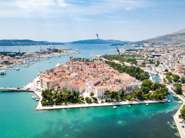 Aerial view of touristic old Trogir, historic town on a small island and harbour on the Adriatic coast in Split-Dalmatia County, Croatia. Flock of gulls or other black birds flying around stock photo