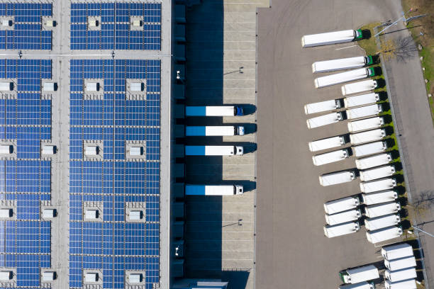 luchtfoto van trucks laden bij logistic center, distributie magazijn met solar fotovoltaïsche panelen - zonnepanelen warehouse stockfoto's en -beelden