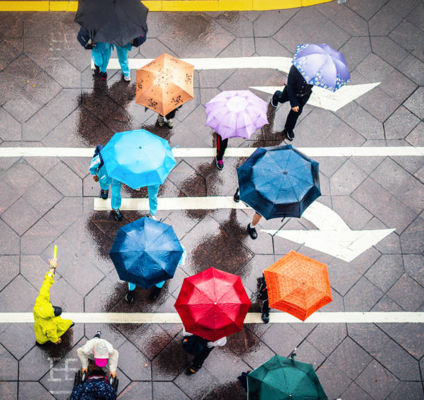 Aerial view of walking people using colorful umbrellas in rain stock photo
