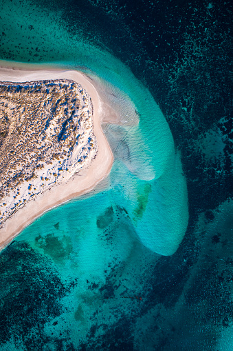 Aerial view of white sand beach coastline with teal blue ocean and reef