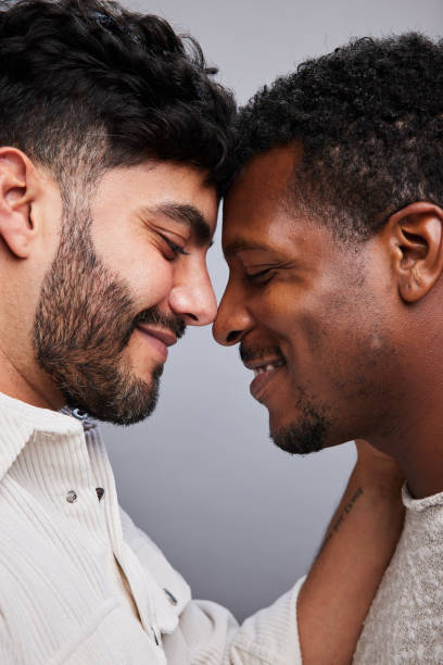 Affectionate young gay couple standing face to face and smiling stock photo