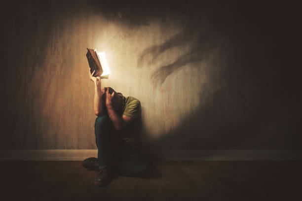 Afraid of the dark A man holds up a Bible to dark shadows battle stock pictures, royalty-free photos & images