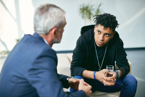 African American adolescent during psychotherapy with mental health professional at counselling center. stock photo