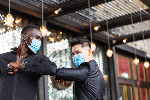 African American black man and Asian friend wearing protective face mask elbow bump greeting for social distancing and new normal business etiquette to prevent Coronavirus infection. copy space African American black man and Asian friend wearing protective face mask elbow bump greeting for social distancing and new normal business etiquette to prevent Coronavirus infection. copy space restaurant culture stock pictures, royalty-free photos & images