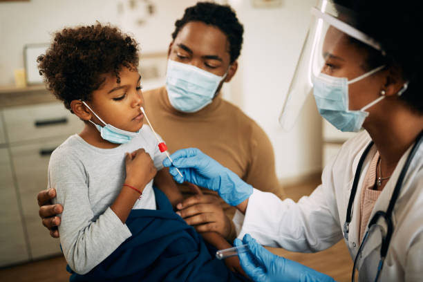 African American boy having PCR test at doctor's office during coronavirus pandemic. African American doctor using cotton swab while PCR testing small boy at medical clinic. at home covid test stock pictures, royalty-free photos & images