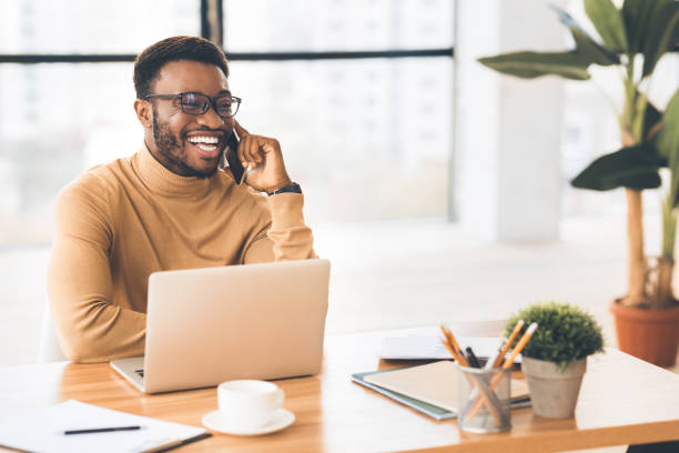 African american businessman gives a phone consultation Phone Consultation. Millennial black man talking to client on mobile phone and smiling, copy space sales occupation stock pictures, royalty-free photos & images