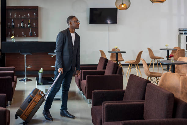 African American businessman in formal wear with luggage is boarding the airplane from airport departure lounge stock photo