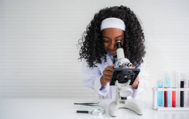 African american child girl student is learning and test science chemical by looking to microscope stock photo