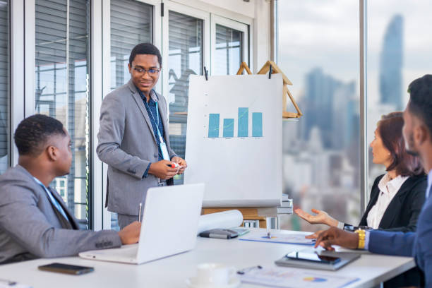 African American executive manager is showing annual report chart to his colleagues in the executive meeting for next year plan with city skyline background for global business and investment stock photo