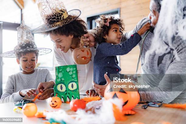 African American family making Halloween decorations at home.