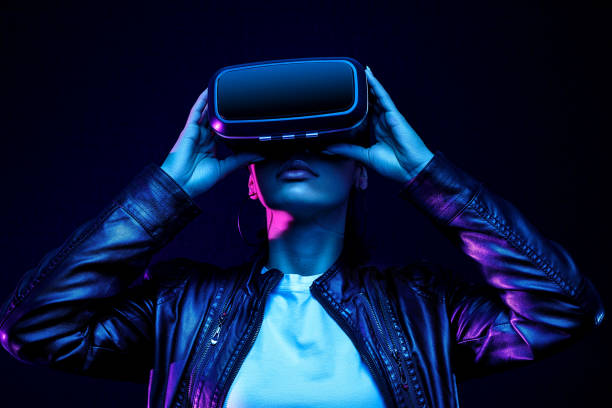 African american girl in vr glasses, watching 360 degree video with virtual reality headset isolated on black background, illuminated by neon lights stock photo