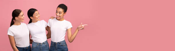 African American Girl Pointing Finger Showing Friends Something, Studio, Panorama Great Offer. African American Girl Pointing Finger Showing Her Friends Something Standing Over Pink Background. Studio Shot, Panorama, Empty Space chinese girl hairstyle stock pictures, royalty-free photos & images