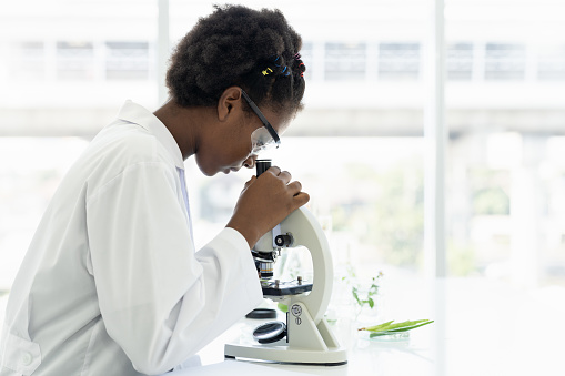 African American girl scientists learning science and doing analysis for germs and bacteria with microscope in the laboratory. Science and education, researcher and discovery concept