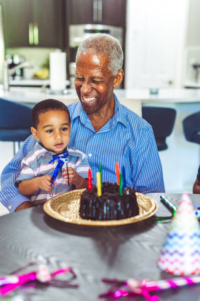 african american grandfather with grandchild at a home birthday celebration - grandparents vertical imagens e fotografias de stock