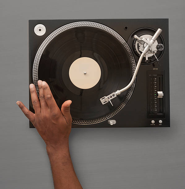 African American Hand spinning record on turn table An overhead photo of a male African American hand spinning or playing a record on an record player / Turn Table.  Logos have been removed from player. turntable stock pictures, royalty-free photos & images
