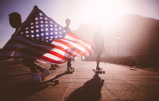 Teenage African American skater flying an American flag past the camera