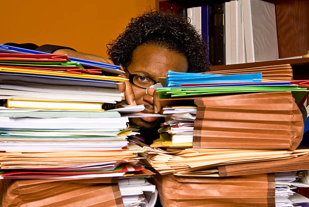 African American male buried behind a pile of folders stock photo