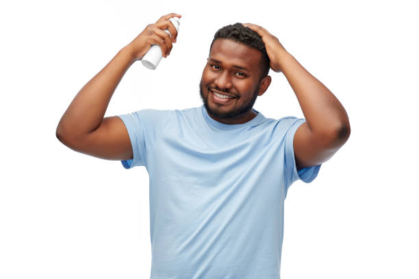 african american man applying hairspray to hair stock photo
