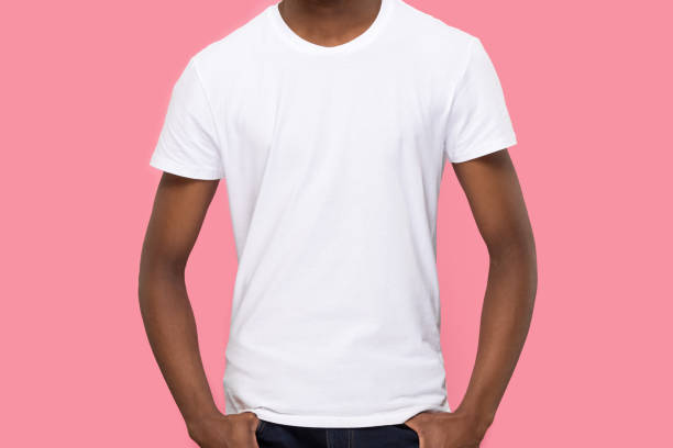 African American man in blank white t-shirt front mock up Young African American man, male model wearing blank white t-shirt front mock up and jeans, demonstrate clothes design template copy space for print, isolated on pink studio background blank t shirt stock pictures, royalty-free photos & images