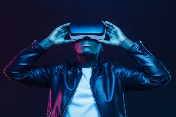 homem do americano africano em vidros do vr, prestando atenção ao vídeo de 360 graus com os auriculares da realidade virtual isolados no fundo preto - gamer - fotografias e filmes do acervo