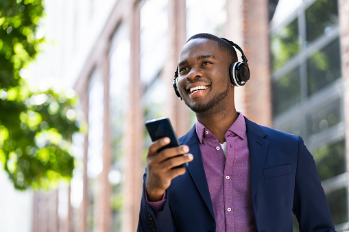 African American Man Listening Music On Wireless Headphones Outside