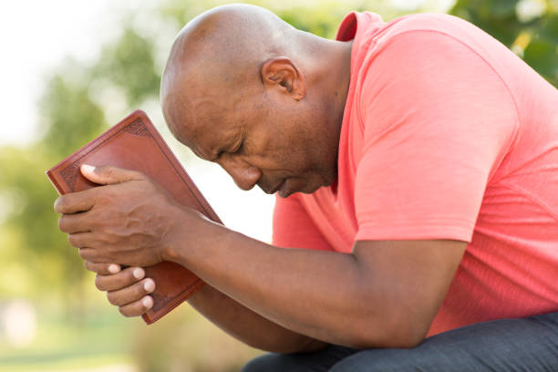African American man praying and reading the Bible. stock photo