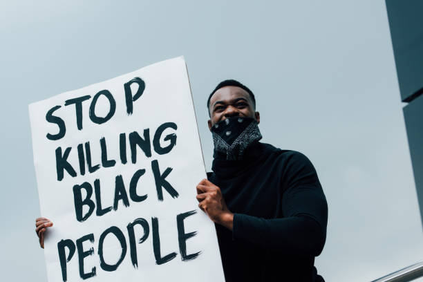 african american man with scarf on face holding placard with stop killing black people lettering outside african american man with scarf on face holding placard with stop killing black people lettering outside anti racism stock pictures, royalty-free photos & images