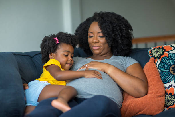 African American pregnant mother and her daughter. African American mother and daughter smiling at home. embracing photos stock pictures, royalty-free photos & images