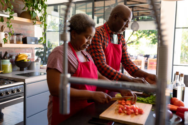 African american senior couple cooking together in kitchen stock photo