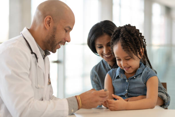 African American woman attends doctor's appointment with young daughter An African American mother is holding her young daughter on her lap. The child is having an appointment at a medical clinic. They are seated at a table across from the medical professional. The ethnic male doctor is teaching the mother and daughter about diabetes and how to use an insulin pen. allergy test stock pictures, royalty-free photos & images