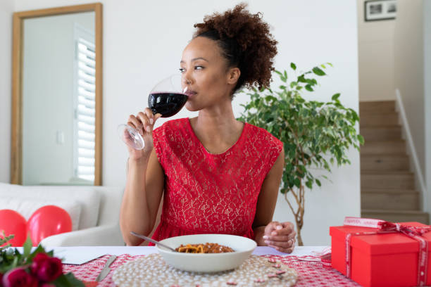 African american woman drinking wine on videocall at home stock photo